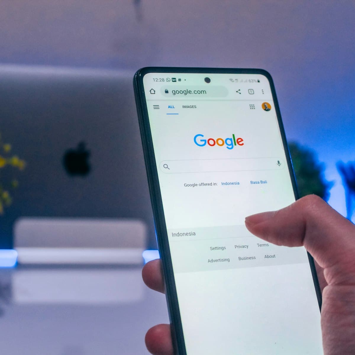 A hand holding a phone open to a Google search